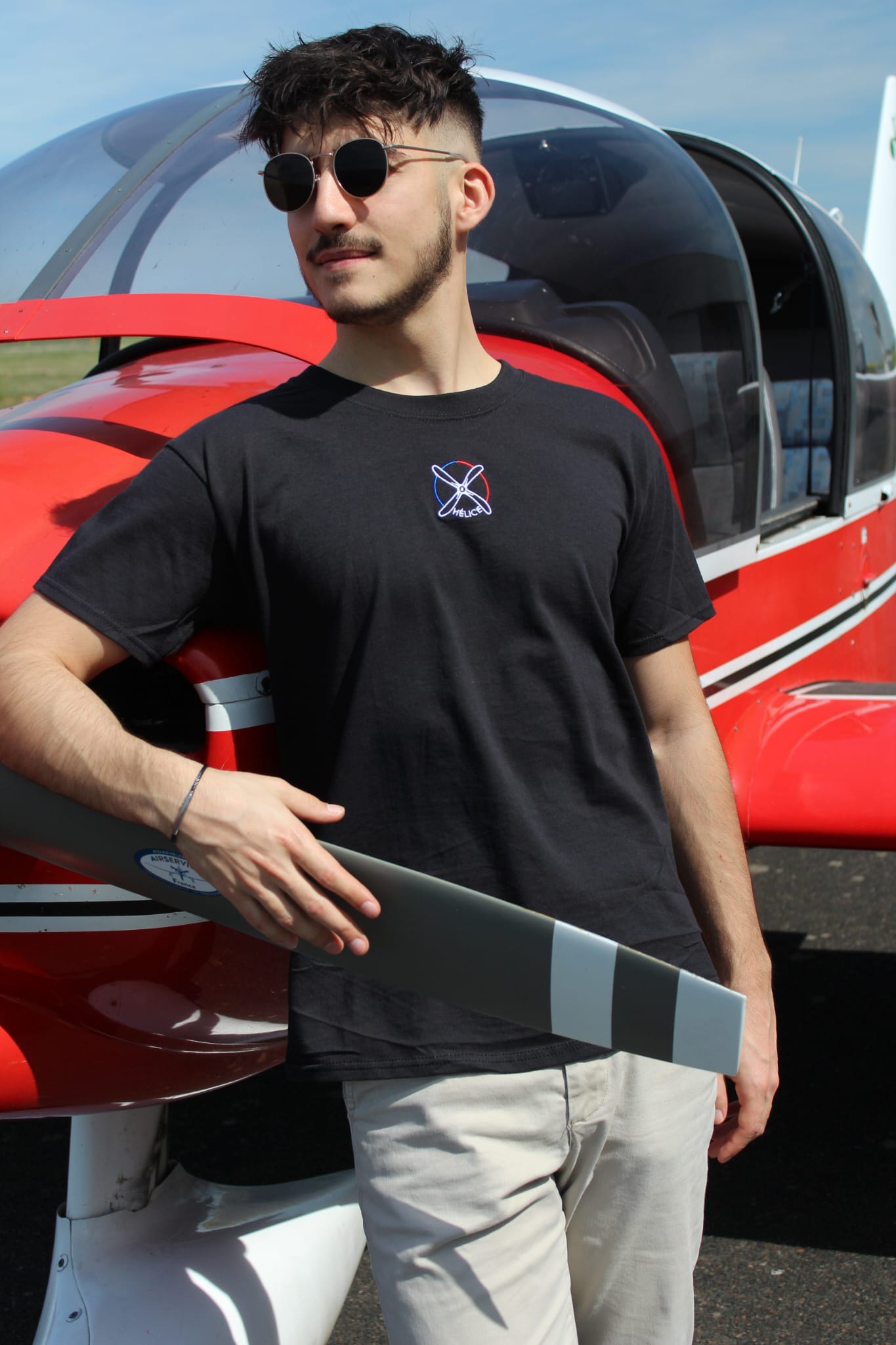 Pilote d'avion portant le tee-shirt noir 123.5 helice-aero.fr